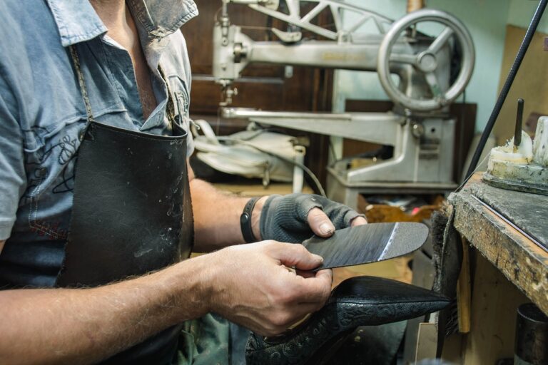 Image shows a cordwainer operated a stitching machine whilst sizing a new sole.